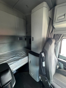 Cab interior of 2022 Kenworth T680 sleeper cab showing bunk area and overhead cabinets.