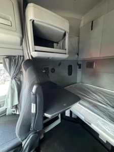 Kenworth T680 sleeper cab interior showing bunk area and fold-down table with overhead compartments.