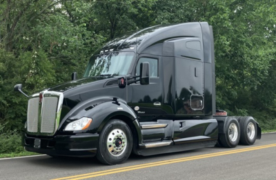 Kenworth T680 tractor trailer in black, side view, showing wheelset and sleeper cab.
