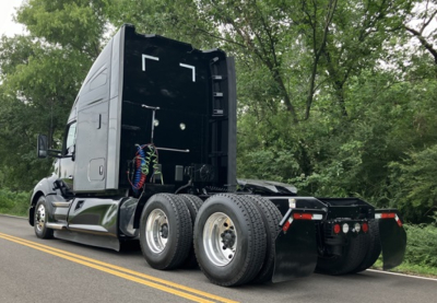 Kenworth T680 tractor conventional sleeper rear view showing dual rear axles, fifth wheel hitch, and exposed air lines.