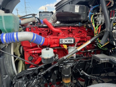 Kenworth T680 engine bay showing Cummins X15 red engine block and various hoses.