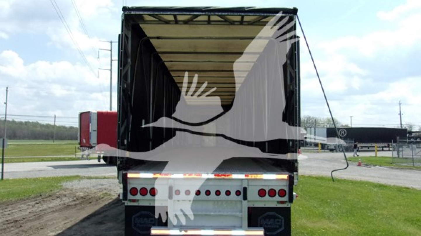 Trailer rear view with open curtainside cargo area showing ramps and taillight assembly.