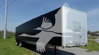 Trailer side with black and white graphic of a flying bird logo, rear doors, gray and black color scheme, no visible text.