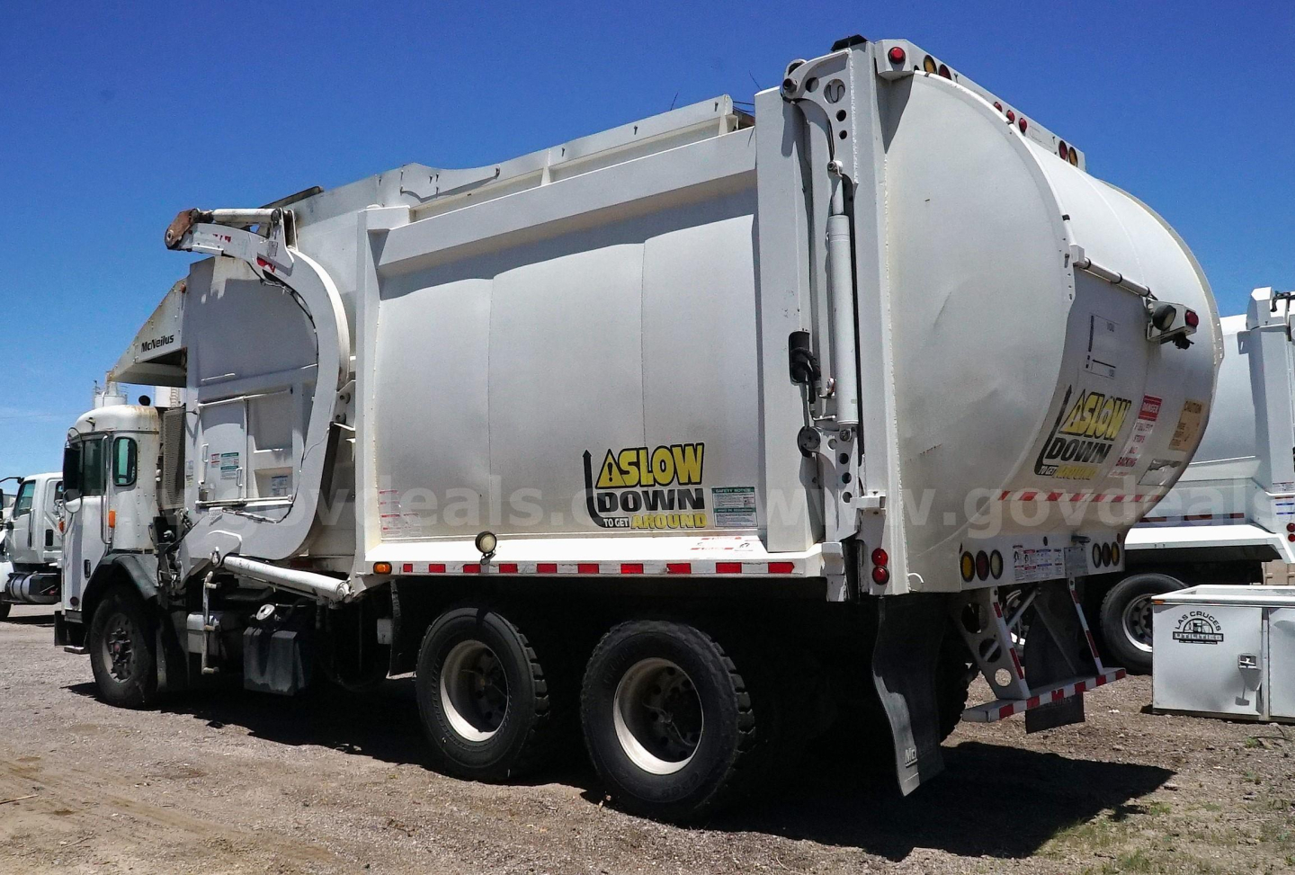 Peterbilt 320 refuse hauler rear view showing large cylindrical compactor body and hydraulic arms.
