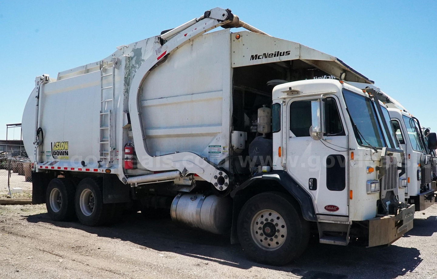 Truck body side view showing large garbage compactor with 'MEMPHIS' branding and rear loader, white cab with side mirrors, dual rear axles.