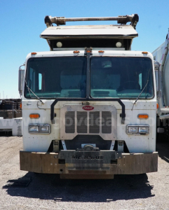Truck front view showing Peterbilt 320 garbage truck with protective bumper and grille, cab windows, and light bars.