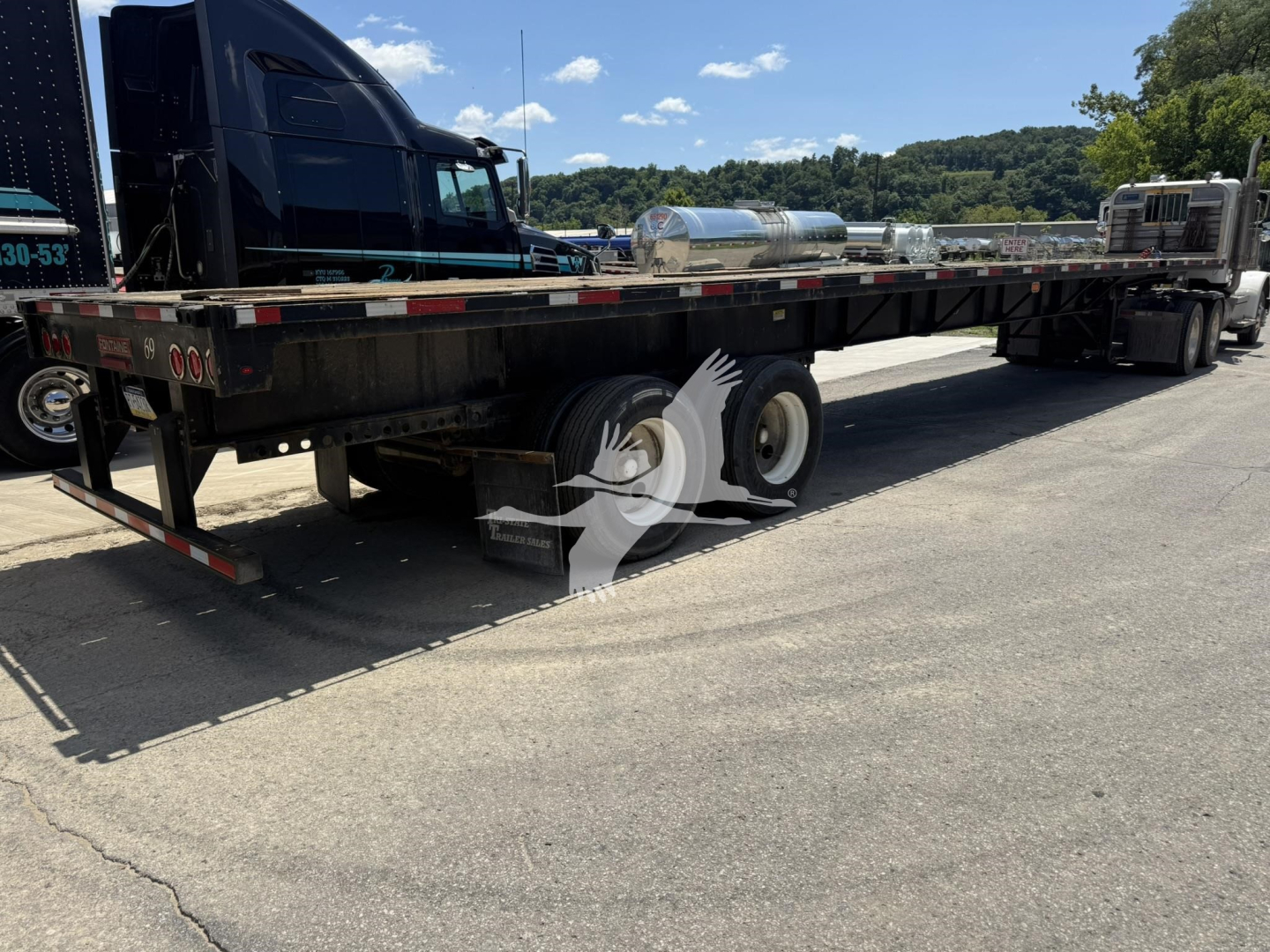Flatbed trailer with dual rear axles and a cylindrical tank mounted on the bed, 2010 Fontaine Xtp 4880Ss2, visible VIN tag and stock number near front.