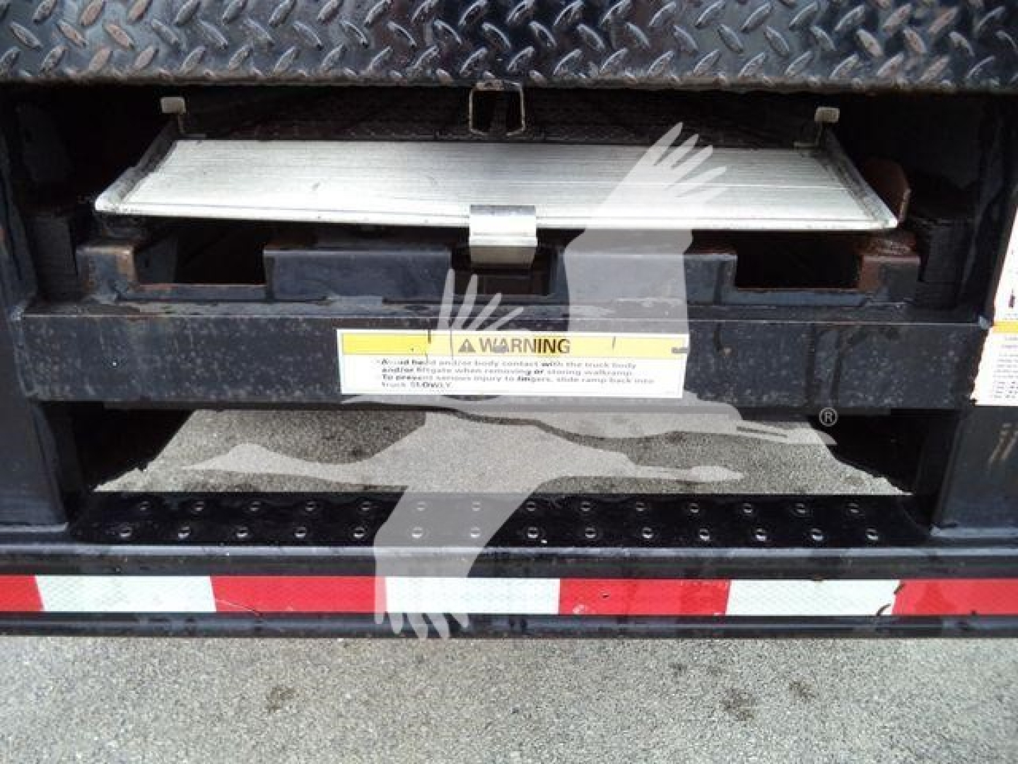 Isuzu NQR truck rear view showing lowered tailgate step and warning label on bumper.