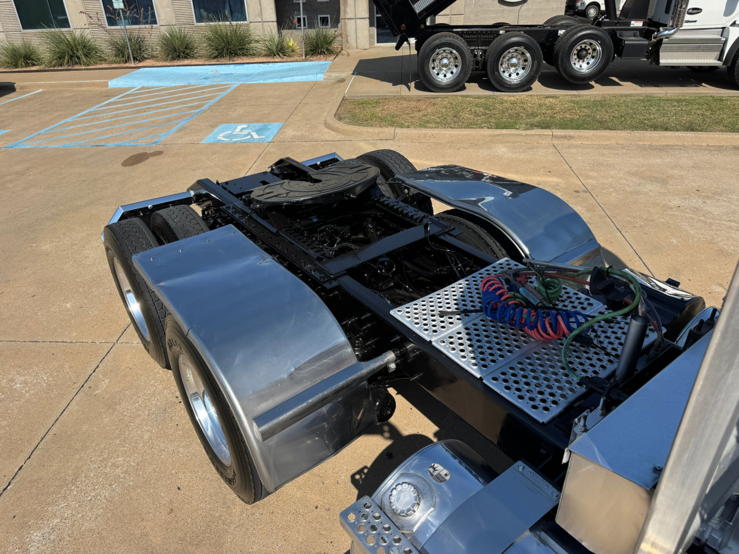 Kenworth W900L tractor rear chassis and fuel/air lines visible with polished aluminum fenders and toolbox; dual rear axles and drivetrain components exposed