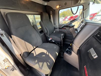 Kenworth W900L truck cab interior showing driver and passenger seats, dashboard, steering wheel, and center console.