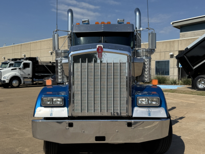 Kenworth W900L conventional daycab front view showing large chrome grille, dual tall exhaust stacks, rectangular headlights, blue fenders, and chrome bumper.