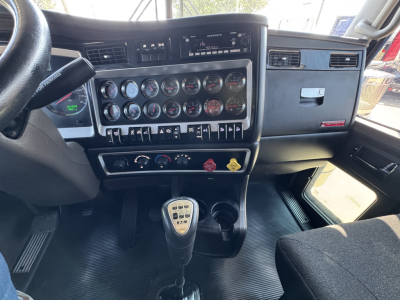 Kenworth W900L interior dashboard and gear shifter with multiple gauges and controls visible.