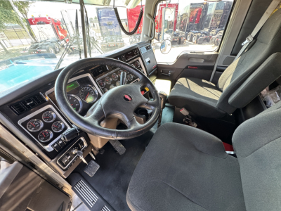 Kenworth W900L truck interior showing steering wheel, dashboard gauges, and driver seat.