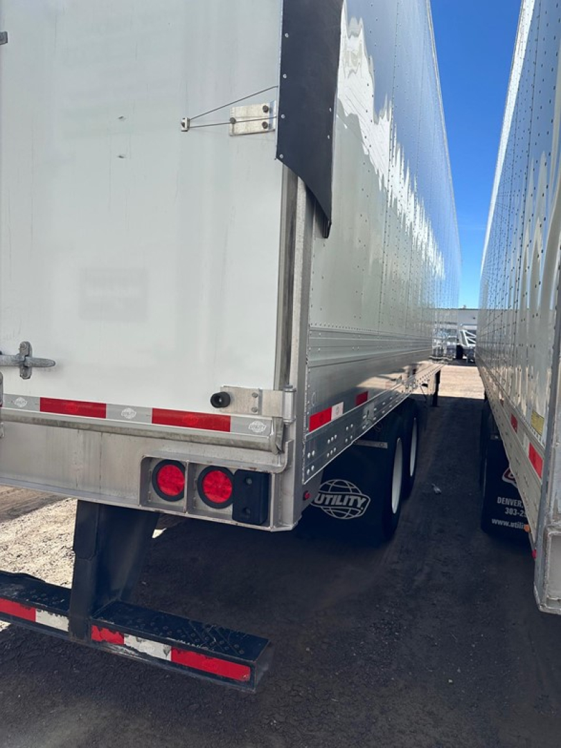 Trailer rear and side view showing Utility 4000dx Tbr trailer with dual rear lights, mud flaps, and reflective safety stripes.