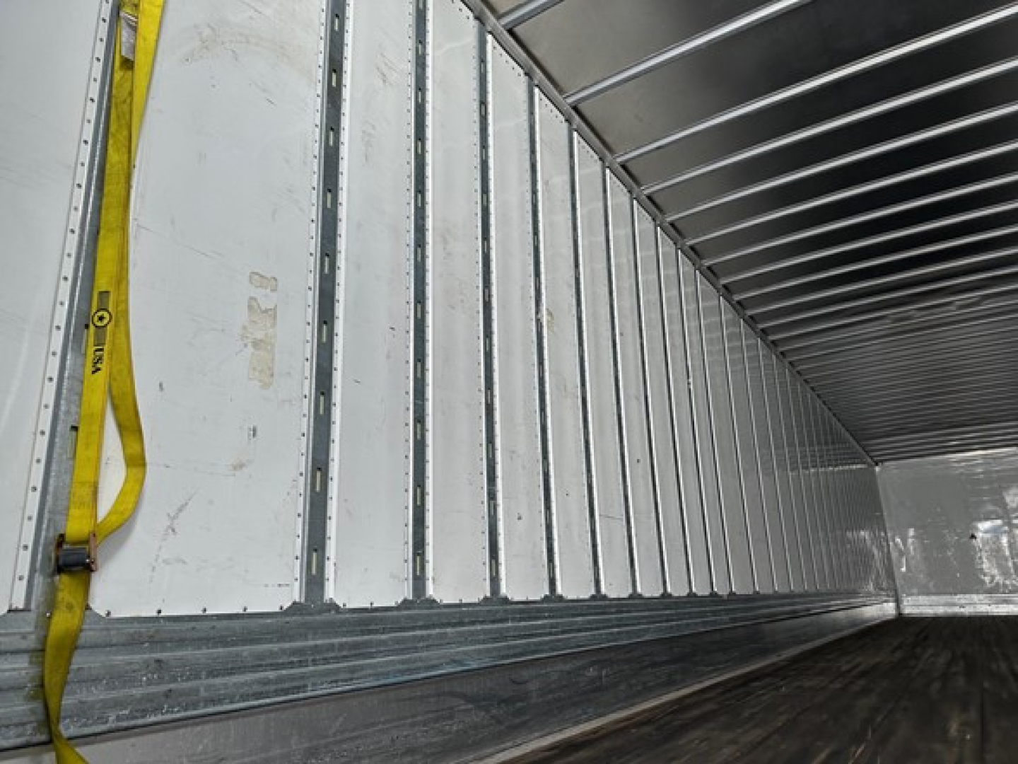 Trailer interior showing metal side walls with vertical ribs and a yellow strap along the left wall.