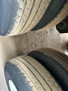Tandem axle trailer tires with wear lines visible, close-up view of rubber treads.