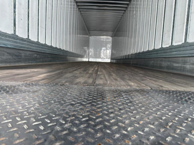 Interior of a Utility 4000dx trailer showing metal diamond plate floor and side walls, empty cargo space, taken from near floor level.