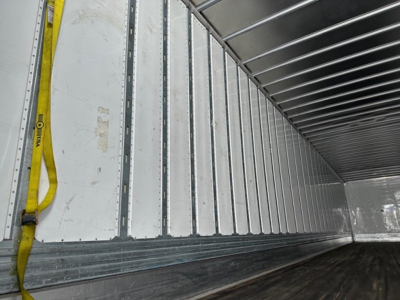 Trailer interior showing metal side walls with vertical ribs and a yellow strap along the left wall.