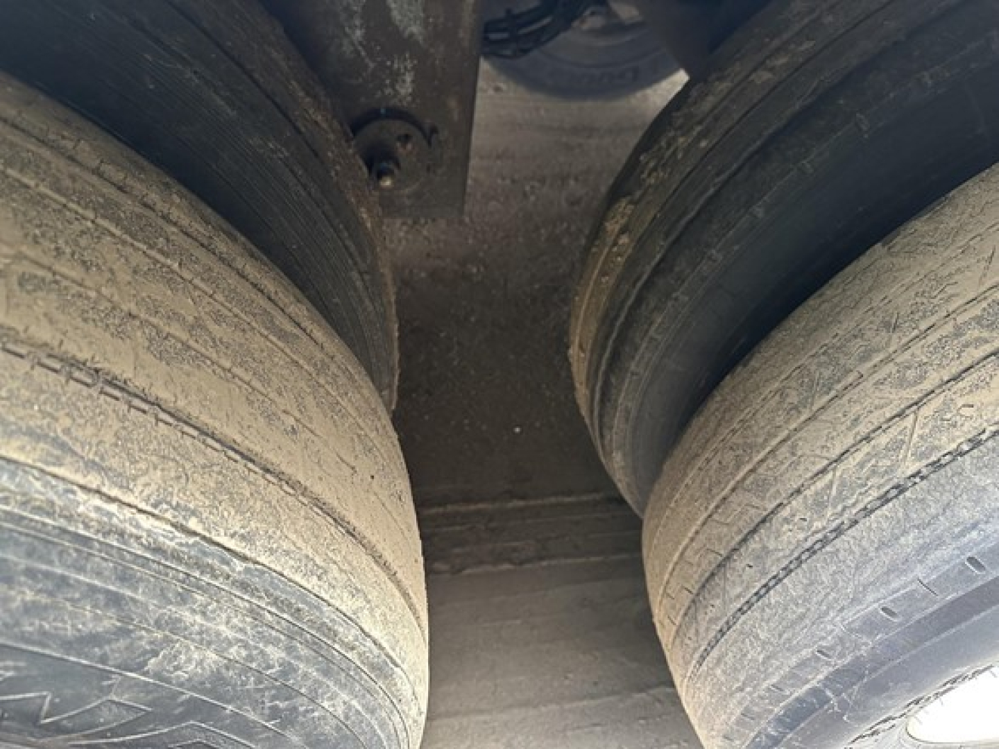 Trailer dual tires view showing worn tread and grime on semi-trailer wheels undercarriage