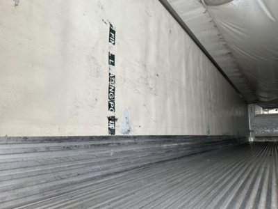 Trailer interior of a 2009 Utility 3000R reefer showing ribbed metal floor and insulated side wall with some stickers.
