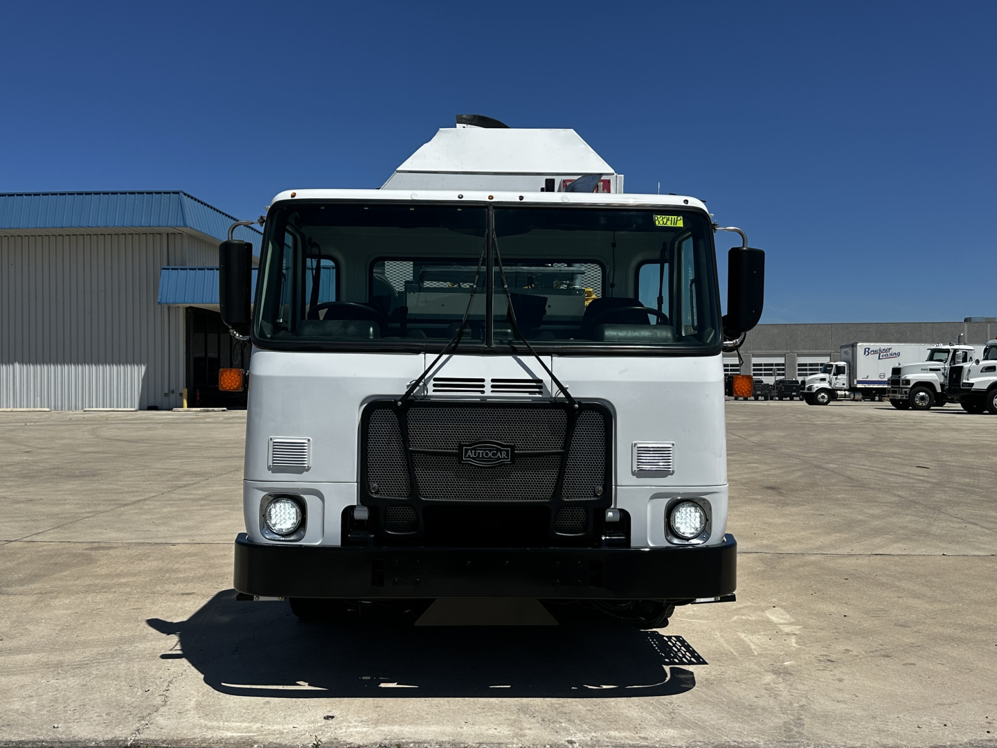 Autocar XPEDITOR truck front view showing grille, headlights, and bumper, with white cab and black grille guard.