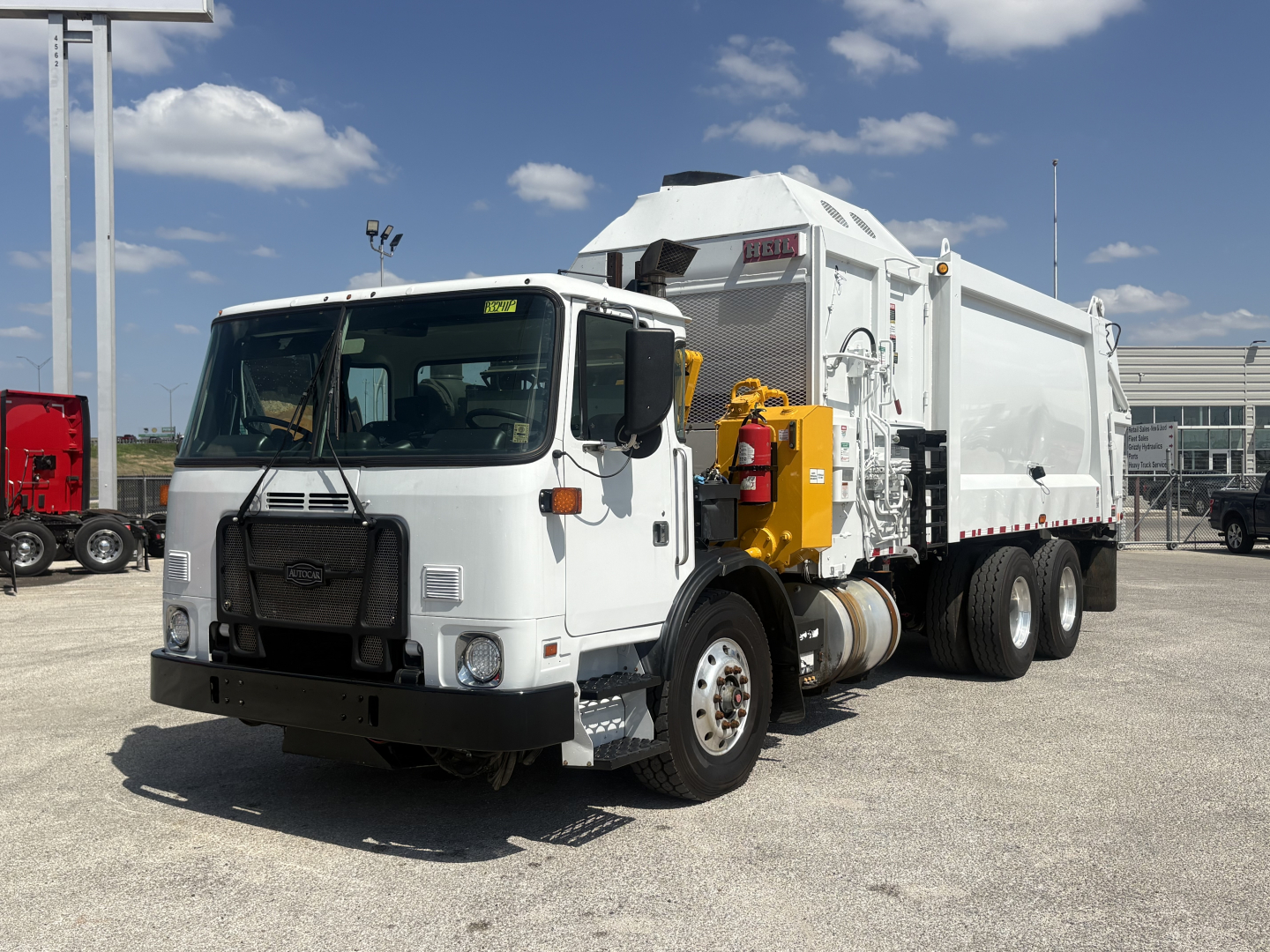 Garbage truck 2019 Autocar XPEDITOR in white with rear-compactor body, side yellow hydraulic system, black front bumper, and dual rear axles parked in lot.
