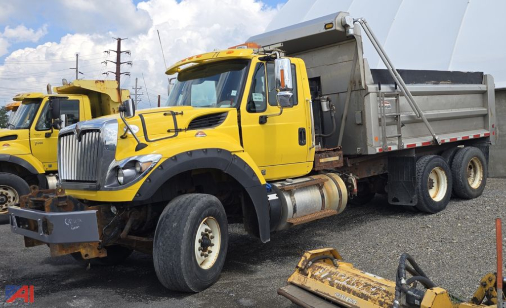 Side/front view of a yellow 2016 International WorkStar 7600 dump truck with dump bed, large front grille, dual rear axles, and heavy-duty tires.