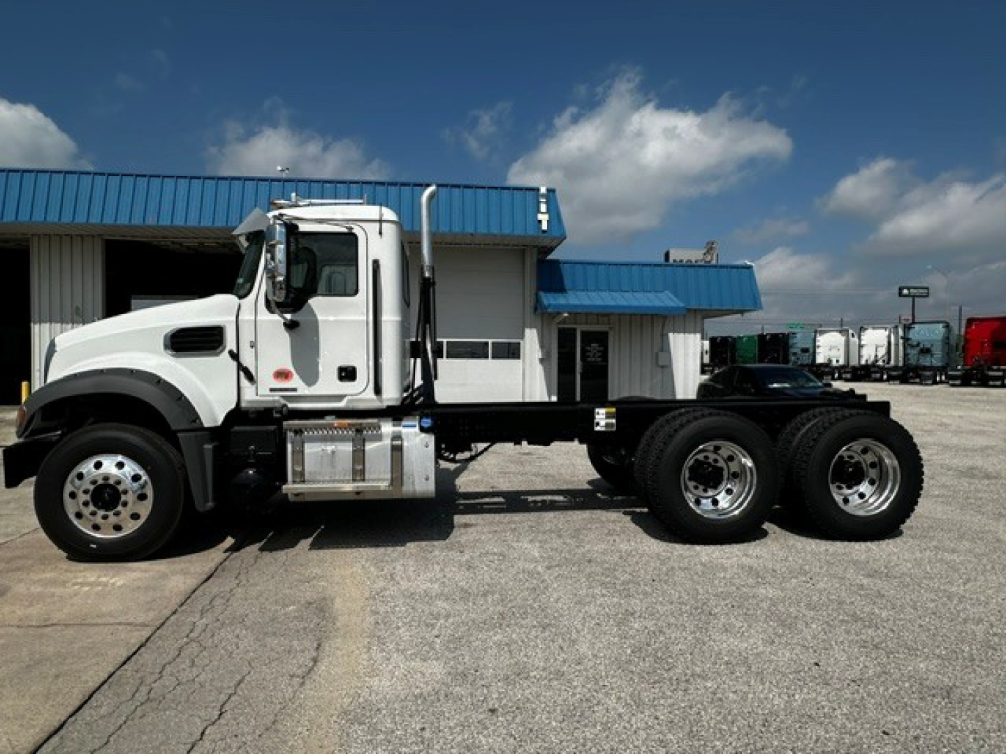 Mack GR64F cab and chassis truck side view showing the front cab, dual rear axles, and silver fuel tank with chrome steps.