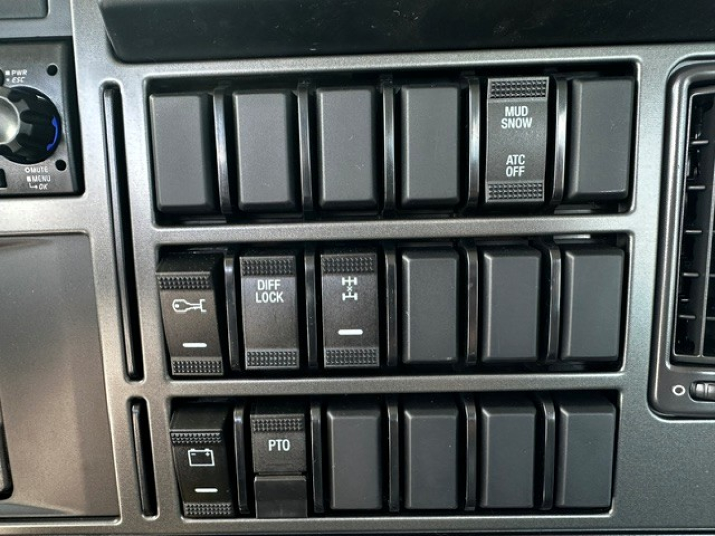 Dashboard switch panel showing multiple rocker switches and labels, including DIFF LOCK, PTO, MUD/ SNOW, ATC OFF, and other blank slots.