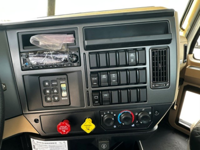 Cab and dashboard of 2027 Mack GR64F showing center console, steering column, ignition area, and climate controls.