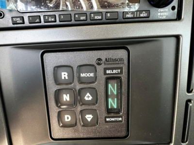 Allison transmission gear selector panel showing R, N, D, mode buttons and green N indicators in a Mack GR64F cab dashboard view.