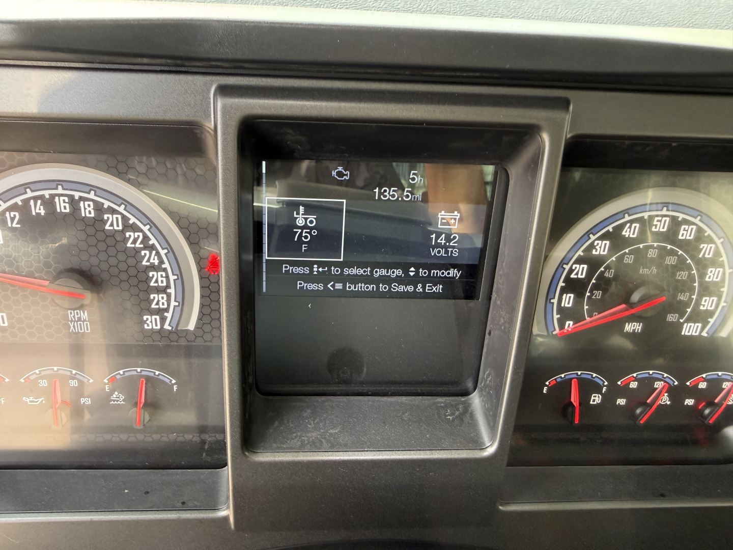 Mack GR64F dashboard cluster showing digital screen with fuel, temperature, and voltage readouts.