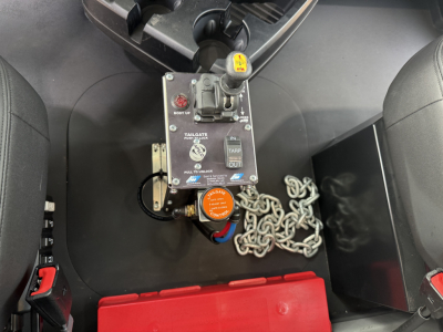 Mack GR64F truck cab interior showing auxiliary control module with labels and a safety chain tether inside storage area