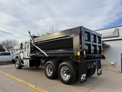 Dump truck rear view showing Mack GR64F dump bed with dual rear axles and chrome wheels in a dealership lot.
