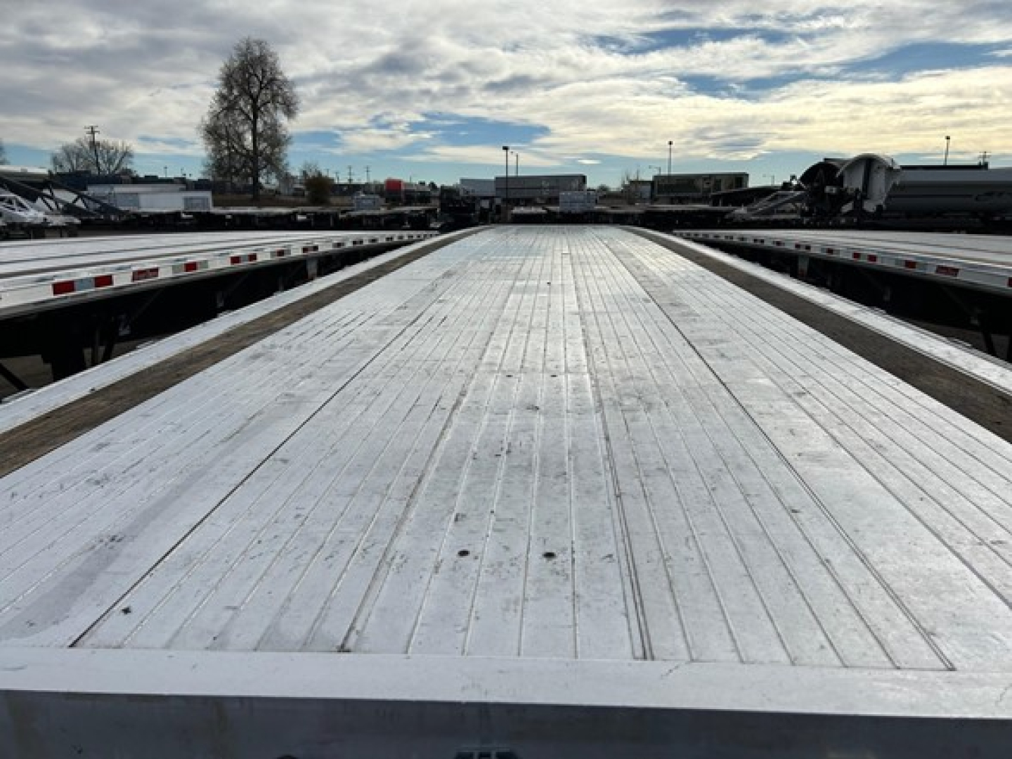 Flatbed trailer deck with ribbed aluminum surface extending toward horizon.