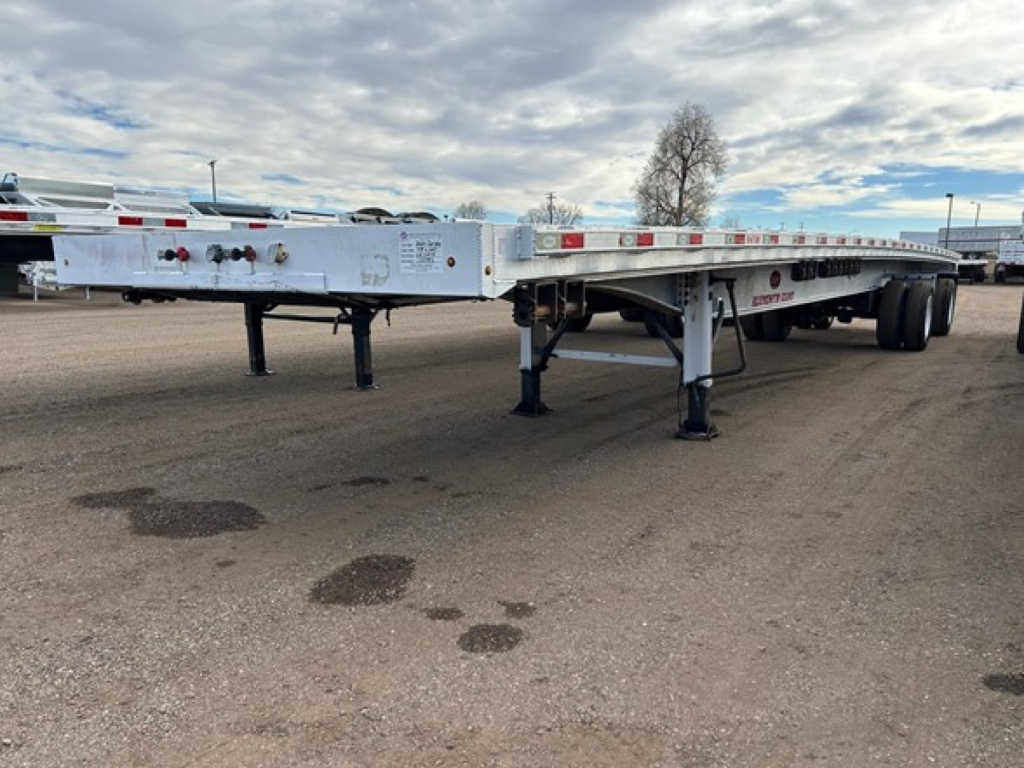 Flatbed trailer showing wheel area and support legs with reflective tape along the sides.