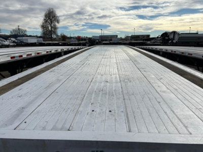 Flatbed trailer deck with ribbed aluminum surface extending toward horizon.