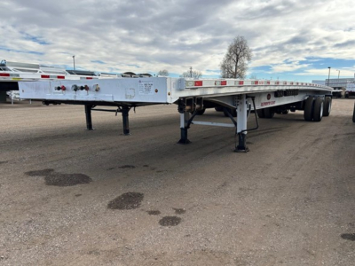 Flatbed trailer showing wheel area and support legs with reflective tape along the sides.