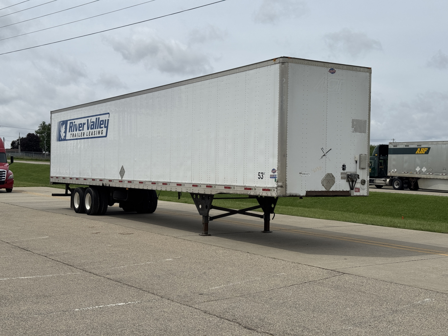Trailer viewed from side with River Valley trailer lease logo, utility 4000 Dx trailer on parked road, front landing gear and wheels visible.