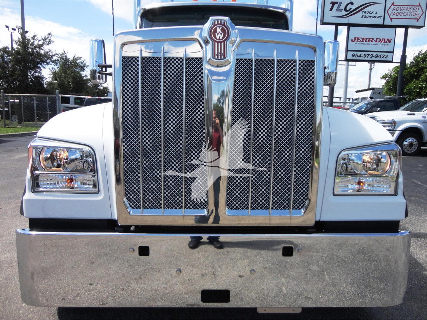 Front view of a white Kenworth W990 truck showing chrome grille, bumper, and headlights.