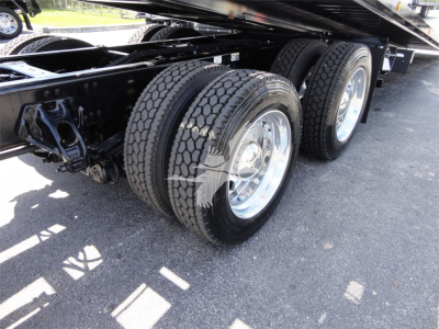 Kenworth W990 trailer with dual rear axles and dual tires, undercarriage visible showing chrome wheel rims and suspension components.