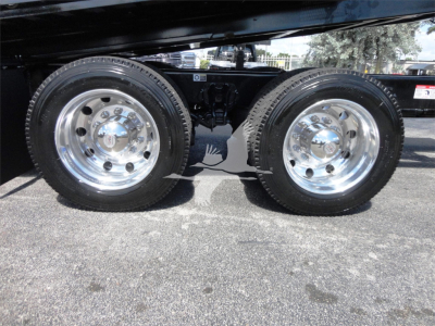 Kenworth W990 side view of dual rear wheels showing shiny chrome rims and suspension undercarriage.