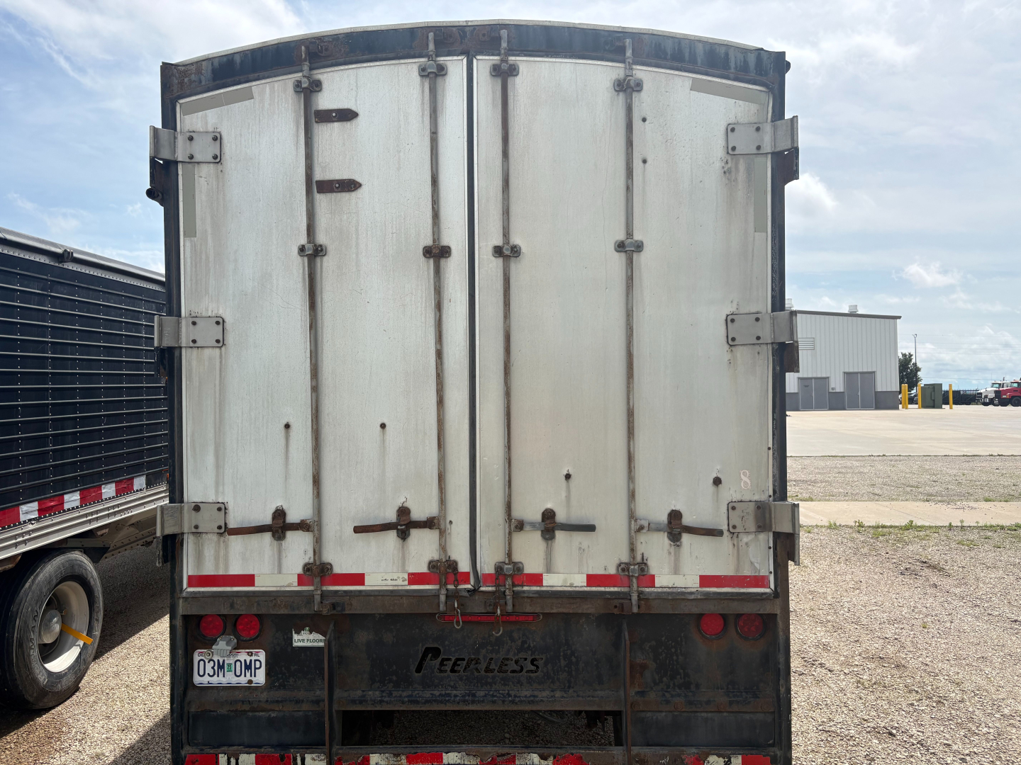 Rear view of a used 2016 Peerless trailer with split rear doors, metal panels, and branding visible on bumper area.