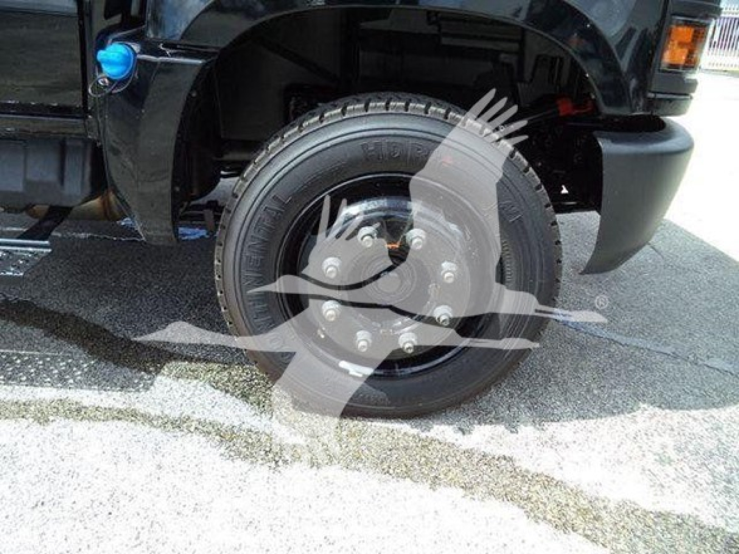 Wheel and front fender of a 2023 Chevrolet Silverado 6500HD with black paint, showing a tire, rim, and part of the front bumper.