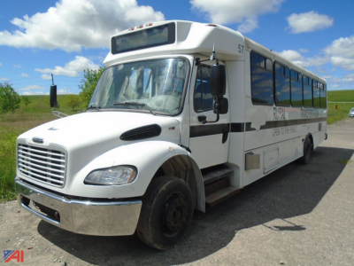 Bus showing Freightliner S2 body with white paint, black stripe, and multiple windows on both sides; 57 number on top front; blue sky background.