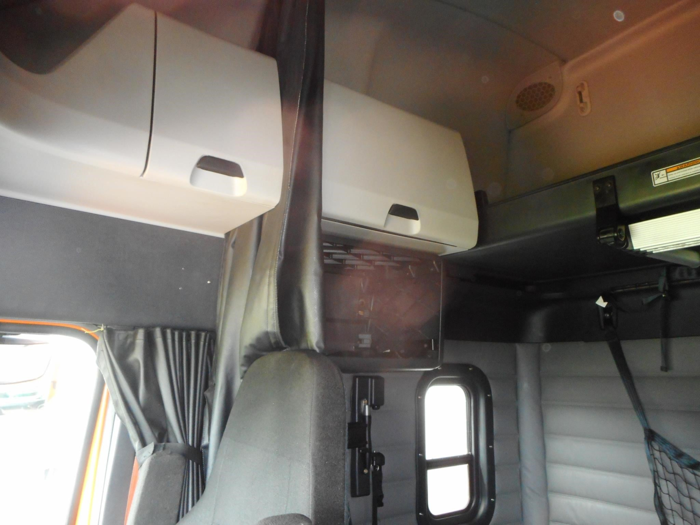 Cab interior of a 2022 Freightliner Cascadia showing overhead storage compartments and sleeper area.