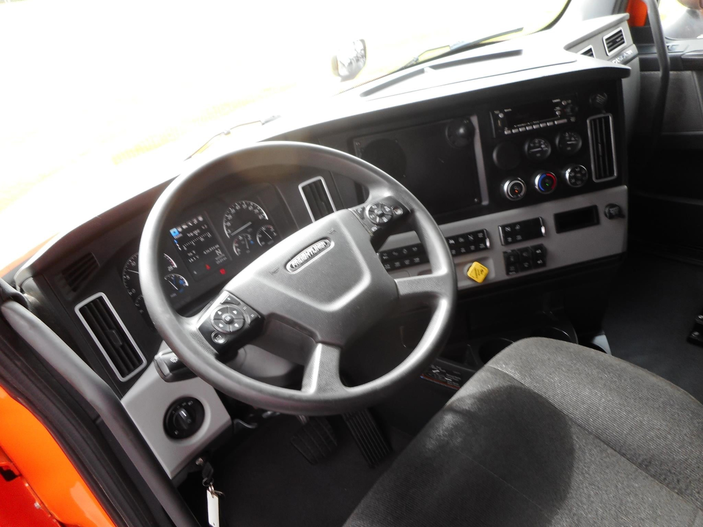 Freightliner Cascadia cab interior showing steering wheel and dashboard with gauges and controls.