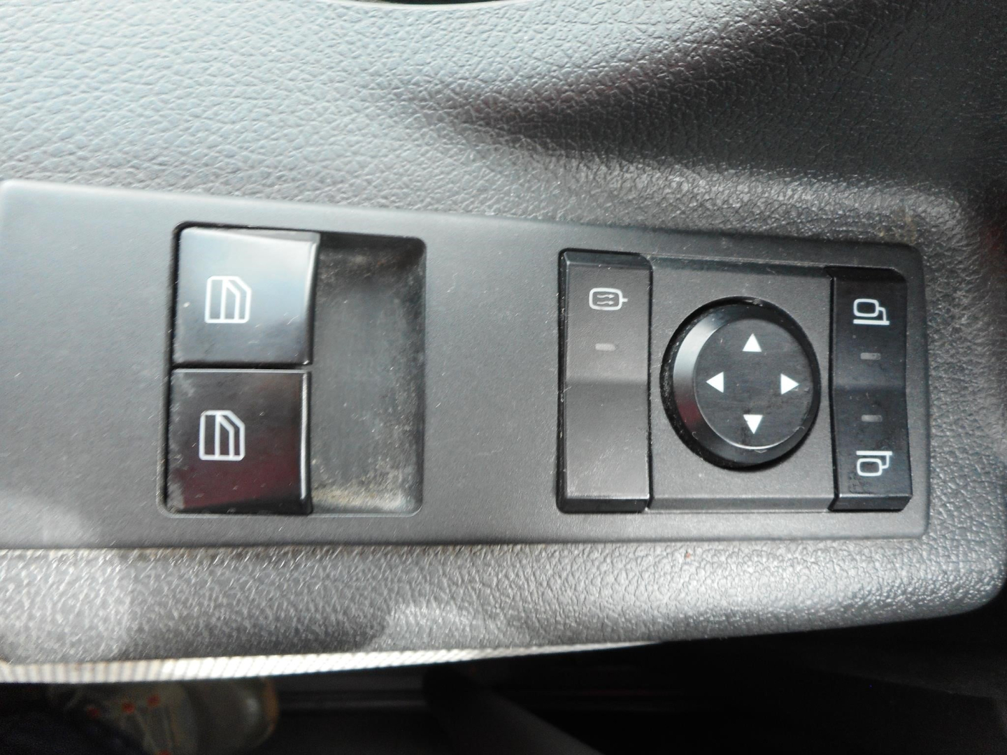 Freightliner Cascadia interior door/window controls panel with two square window switches, a circular navigation pad, and mirror adjustment buttons.
