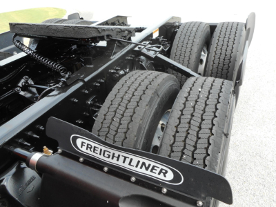 Freightliner Cascadia truck chassis showing dual rear axles, tires, and frame with Freightliner mudflap logo.
