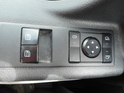 Freightliner Cascadia interior door/window controls panel with two square window switches, a circular navigation pad, and mirror adjustment buttons.